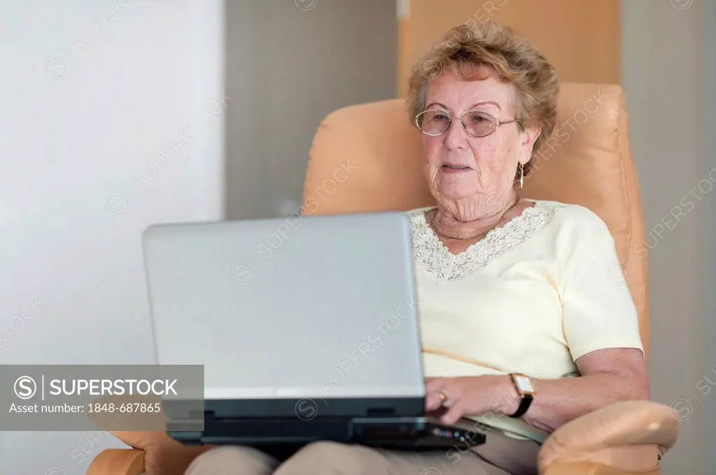 Elderly woman sitting in a chair with her laptop