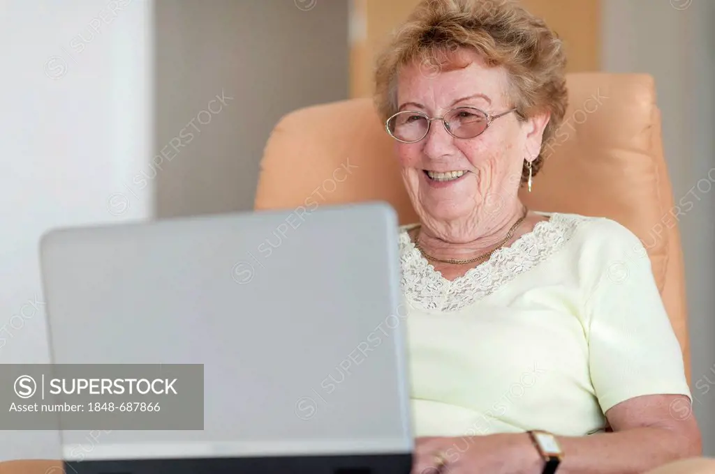 Elderly woman sitting in a chair with her laptop