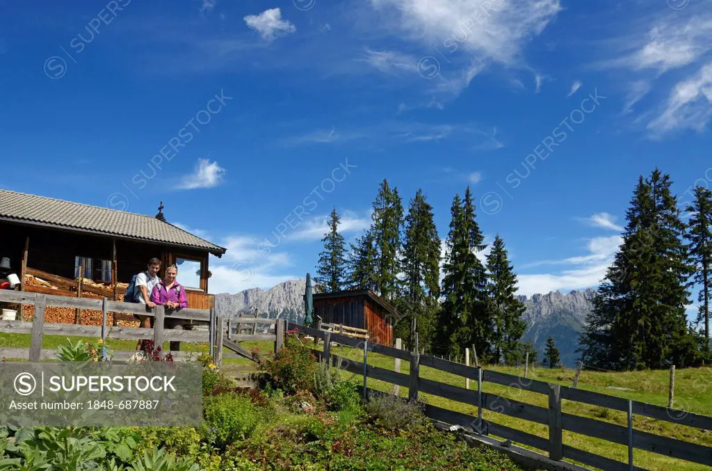 Hiking couple taking a break at Blinzalm, Hartkaiser, view towards the Wilder Kaiser Mountains, Tyrol, Austria, Europe