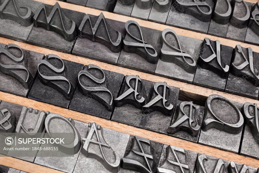 Hot metal setting, old letters made of lead for letterpress printing, cursive script in the letter case