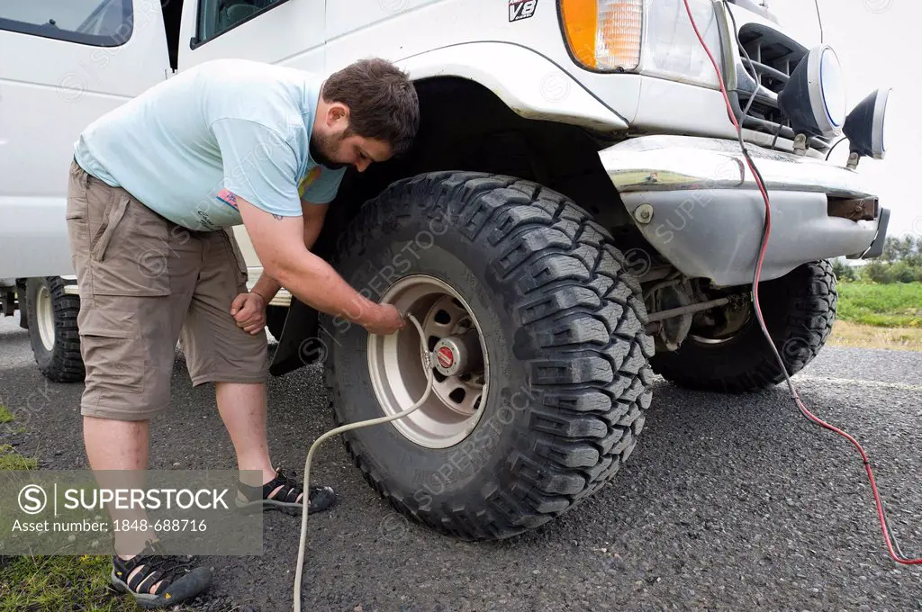 Super jeep driver checking the tire pressure, Iceland, Europe