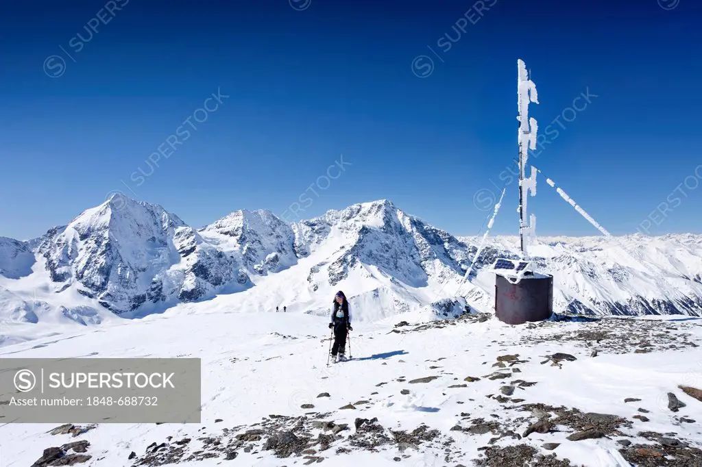 Backcountry skier and a weather station on the peak of Hintere Schoentaufspitze mountain, Sulden in winter, Koenigsspitze mountain, Ortler mountain an...