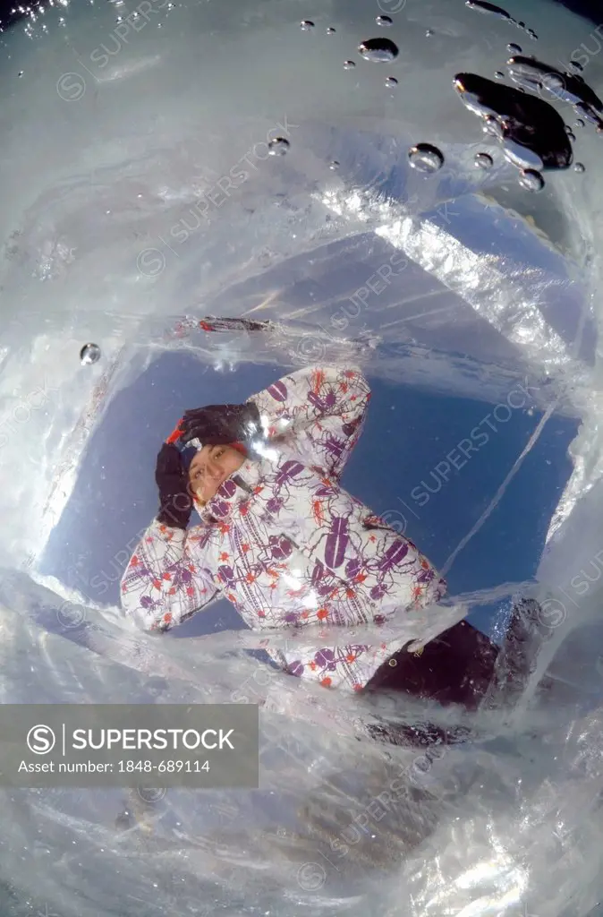 Girl looking through ice-hole, Lake Baikal, Olkhon island, Siberia, Russia, Eurasia