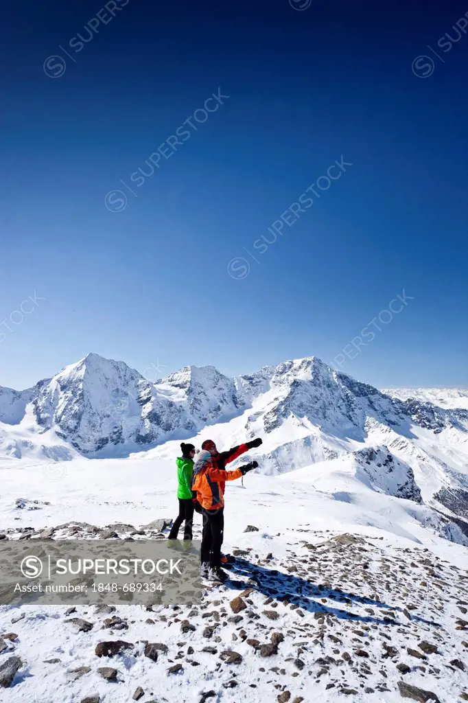 Backcountry skier at the top Hintere Schoentaufspitze mountain, Sulden in winter, Koenigsspitze mountain, Ortler mountain and Zebru mountain at the ba...