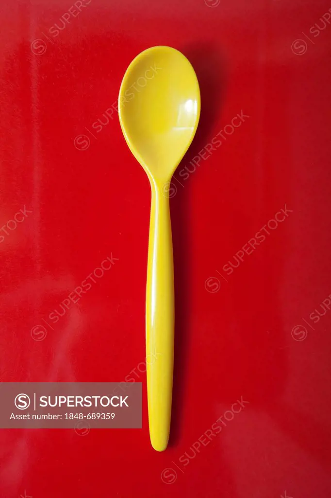 Yellow plastic spoon, egg spoon, on red