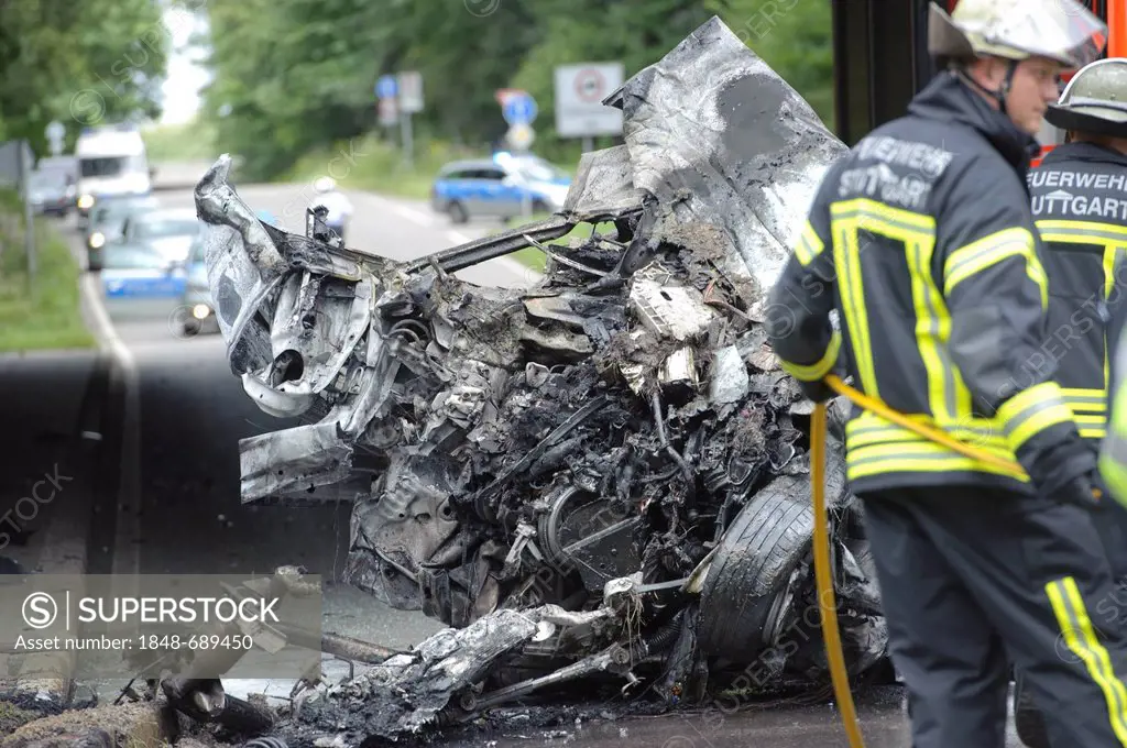 Firefighters attending the wreckage of an Audi car which was destroyed and burned out beyond recognition, Sindelfingen, Baden-Wuerttemberg, Germany, E...