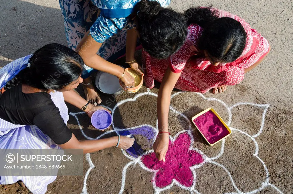 Women making Rangoli, decorative sand designs in the streets of Madurai during a Hindu festival, meant as sacred welcoming area for the deities, Tamil...