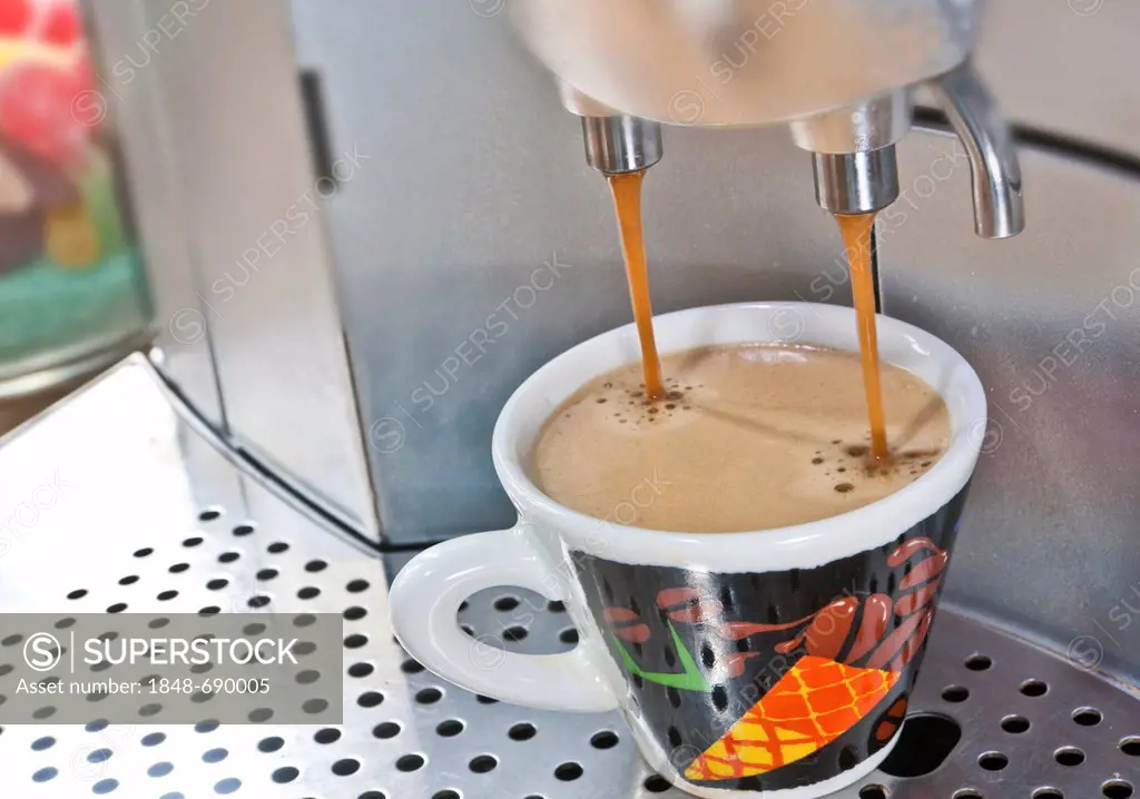 Espresso coffee machine, espresso coffee pouring from a machine into a colourful espresso cup