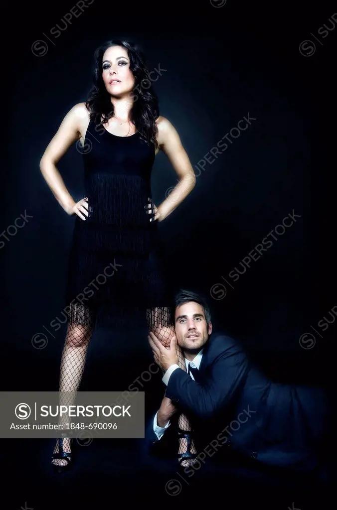 Young man hanging onto the leg of a strong young woman