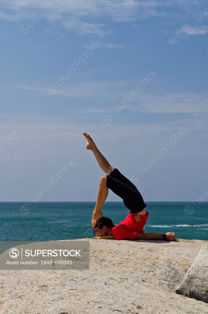 Woman in a yoga position, Salabhasana, by the sea in Kanyakumari, Tamil Nadu, India, Asia