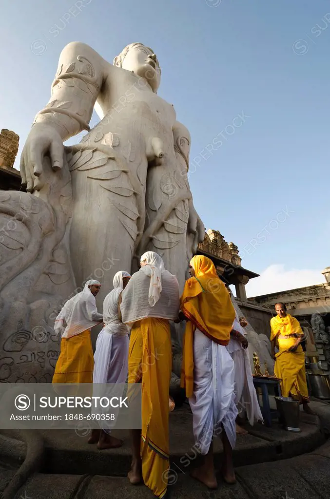 A group of Jain pilgrims doing a special pooja to receive the blessings of Bahubali by the local priests, in front of the statue of Lord Gomateshwara,...