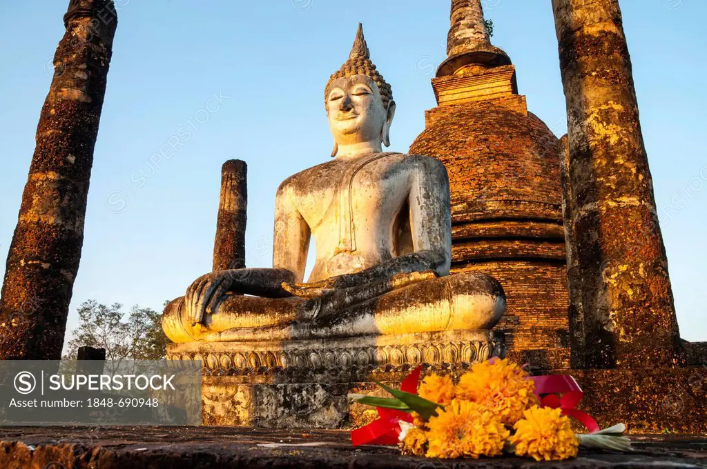 Flowers in front of the seated Buddha statue in Wat Sa Si or Sra Sri temple, Sukhothai Historical Park, UNESCO World Heritage site, Northern Thailand,...