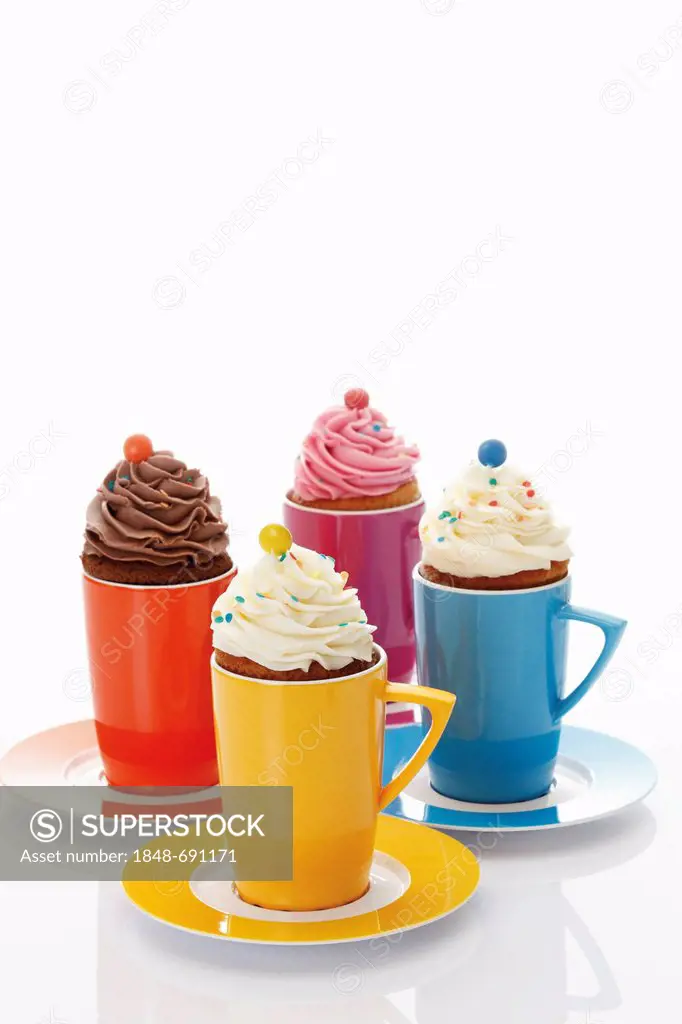 Various cupcakes in colourful coffee mugs