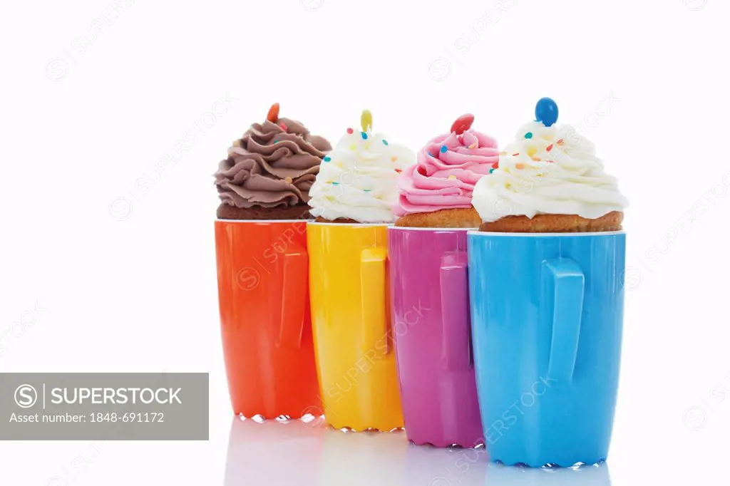 Various cupcakes in colourful coffee mugs