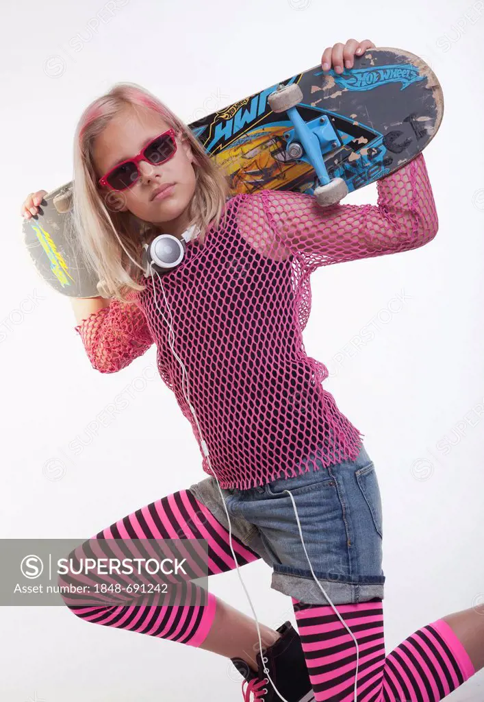 Cool young girl wearing sunglasses, posing with a skateboard