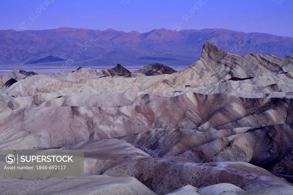 View from Zabriskie Point to Manly Beacon with its eroded rocks coloured by minerals, Panamint Range at back, dawn, Death Valley National Park, Califo...