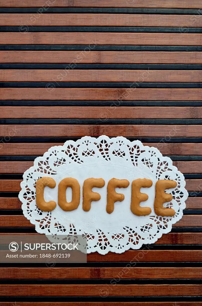 Coffee, written with alphabet biscuits on a paper doily