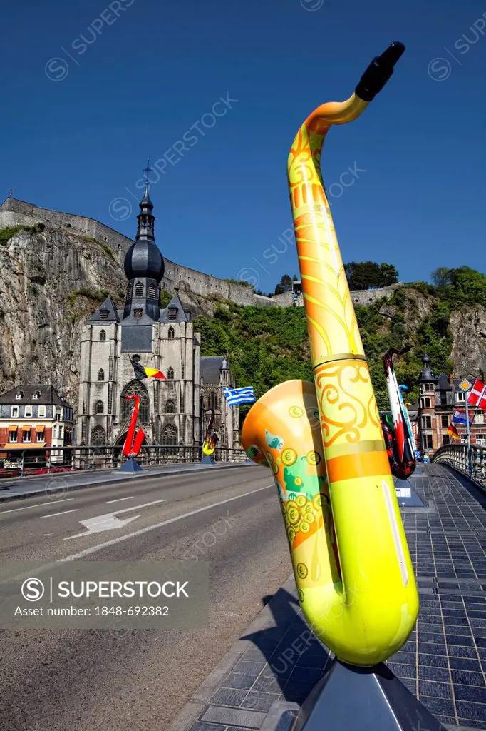 Pont du Charles de Gaulle bridge over the Meuse river with colorful saxophones as memorials to Adolphe Sax, Collegiate Church of Notre-Dame and Citade...
