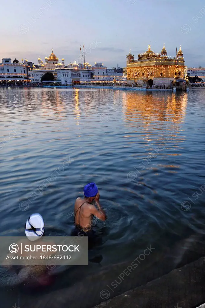 Holy washing of two Sikh men with turbans in the Amrit Sagar, lake of nectar, behind the Sikh sanctuary Harmandir Sahib or Golden Temple, Amritsar, Pu...