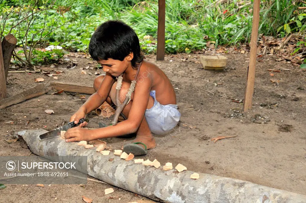 Boy cutting bricks so he can use them for his slingshot, Acampamento 12 de Otubro landless camp, Movimento dos Trabalhadores Rurais sem Terra, a Brazi...