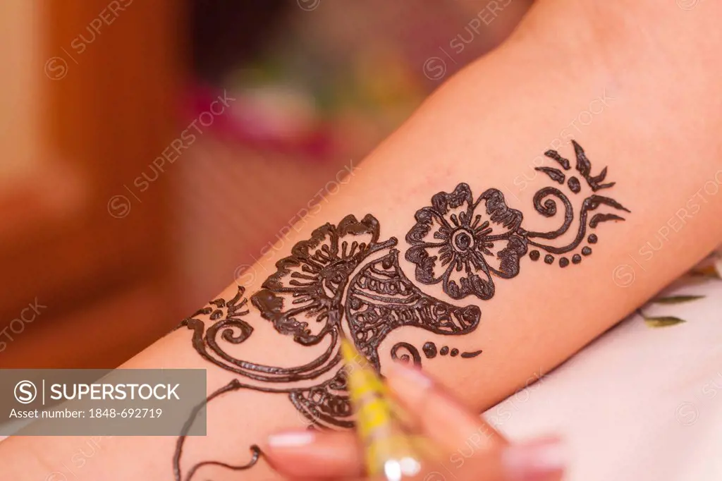 Applying traditional henna pattern on Indian bride's arm