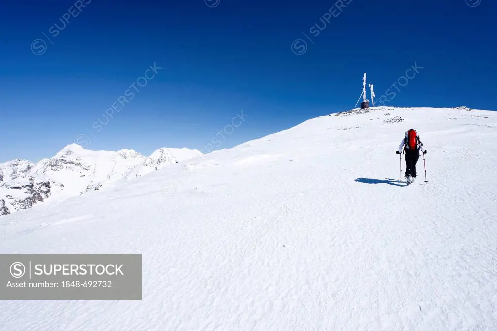 Cross-country skier ascending Hintere Schoentaufspitze Mountain, Solda in winter, looking towards the summit with a weather station, Alto Adige, Italy...