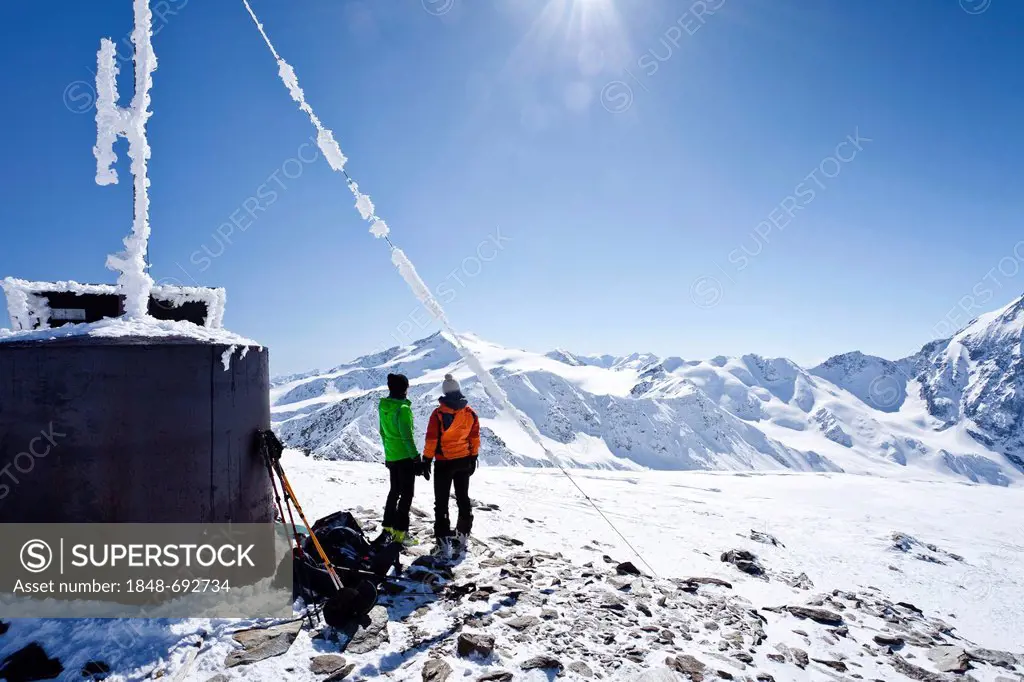 Cross-country skiers beside a weather station on the summit of Hintere Schoentaufspitze Mountain, Solda in winter, looking towards Zufallspitze and Ce...