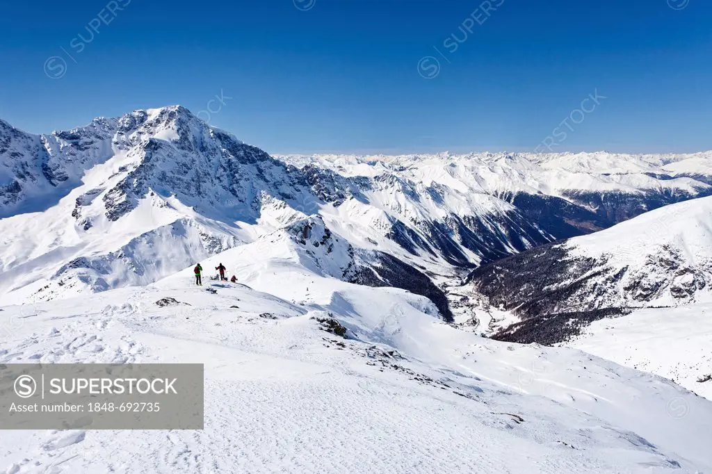 Cross-country skiers descending Hintere Schoentaufspitze Mountain, Solda in winter, looking towards Ortler Mountain and Solda Valley, Alto Adige, Ital...