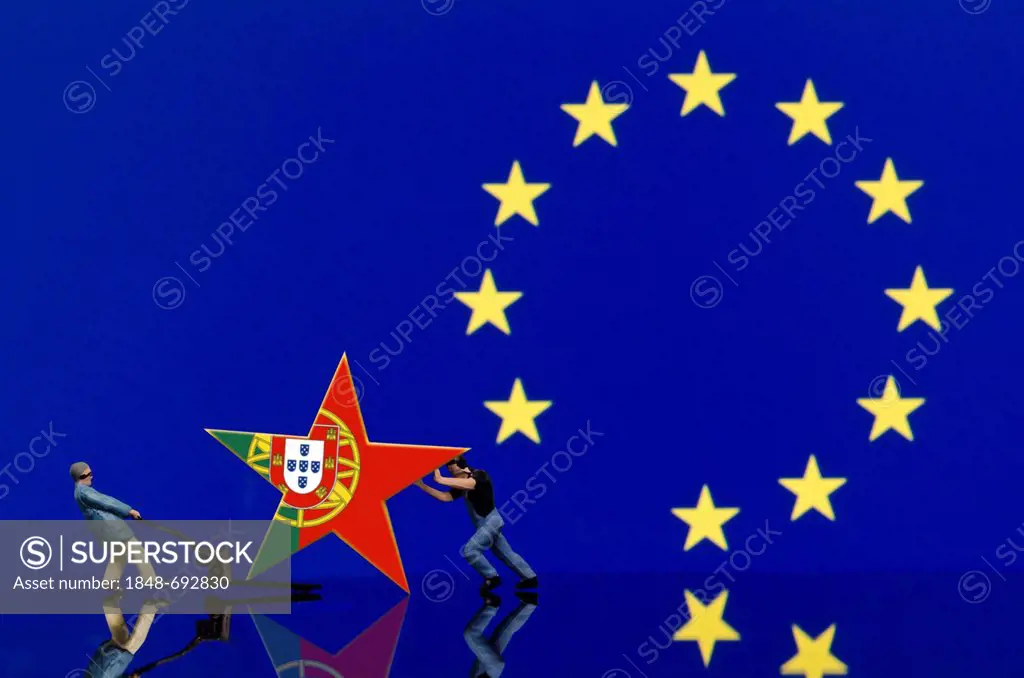 Two miniature warehouse worker figures pushing a star with the Portuguese flag away from the European flag, symbolic image for the euro crisis