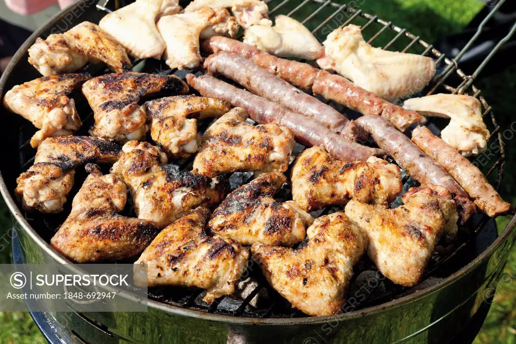 Chicken wings and sausages on a charcoal grill