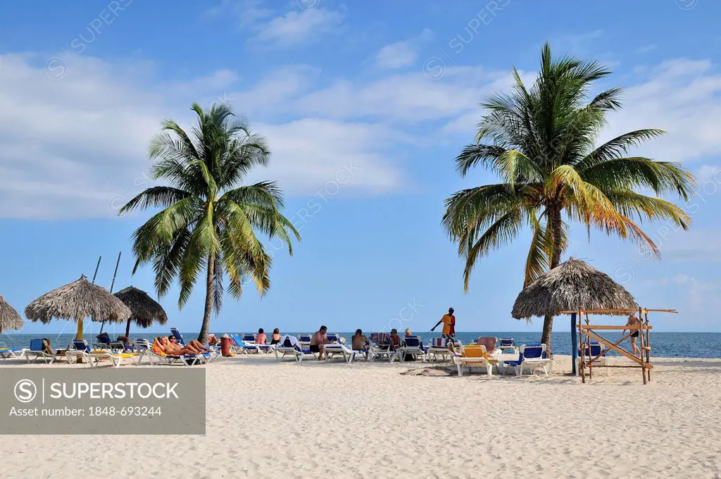 Bathers and palm trees on the beach of Playa Ancón, near Trinidad, Cuba, Caribbean