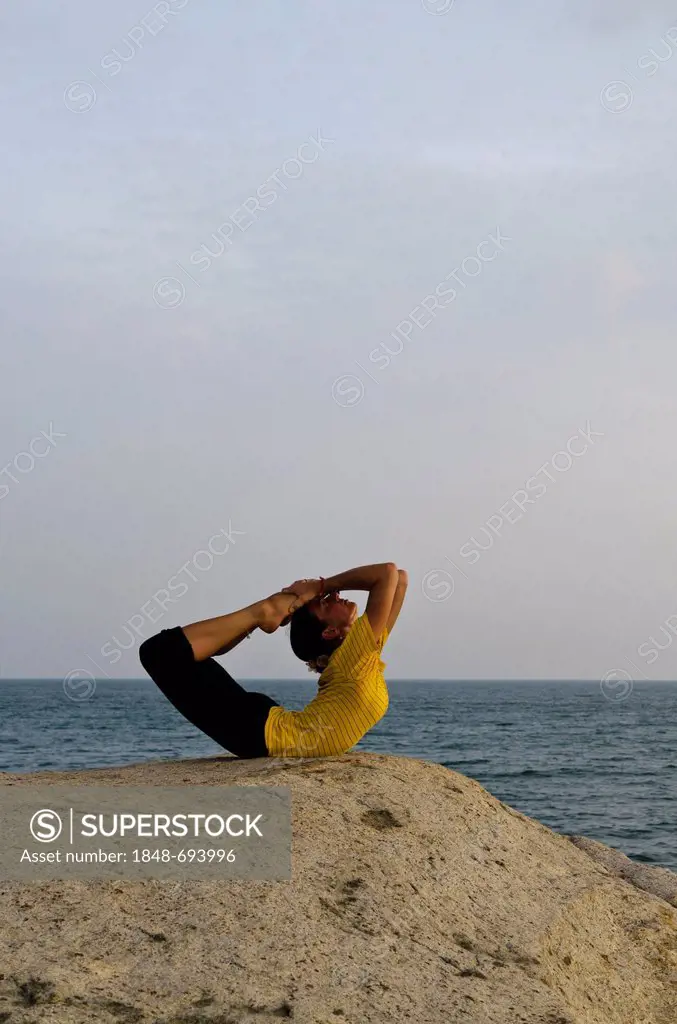 Woman in a yoga position, Dhanurasana, by the sea in Kanyakumari, Tamil Nadu, India, Asia