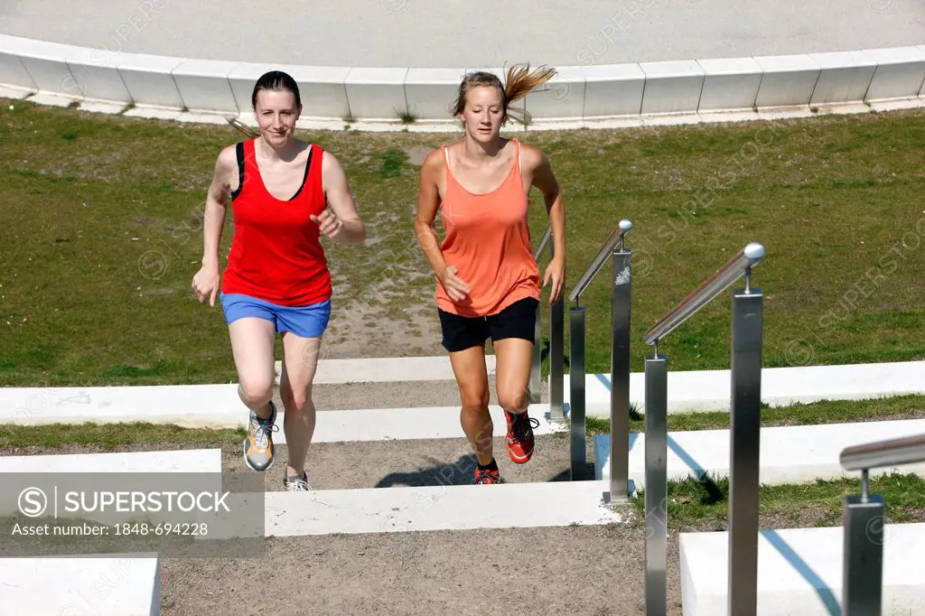 Two recreational runners, young women, 25-30 years, jogging up stairs