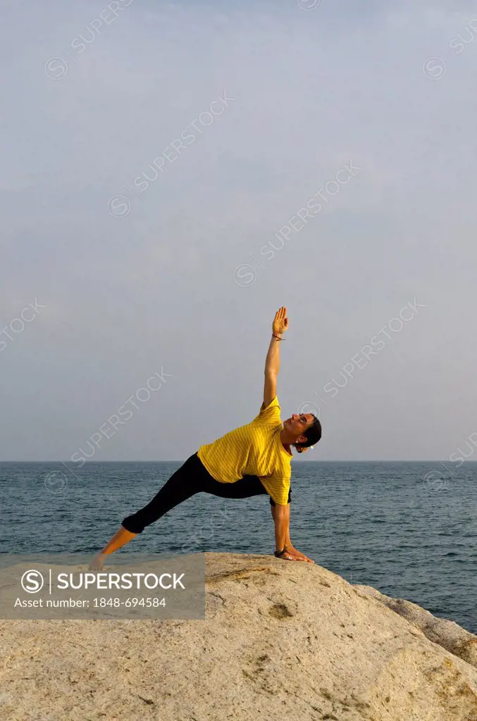 Woman in a yoga position, Utthita-Parshvakonasana, by the sea in Kanyakumari, Tamil Nadu, India, Asia
