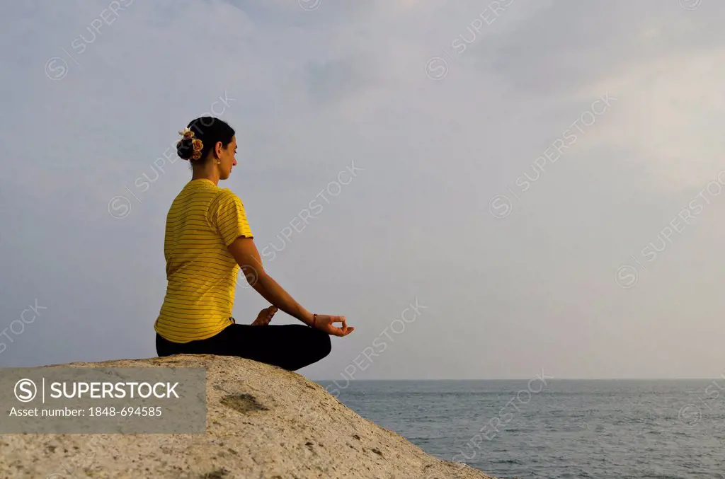 Woman in a yoga position, Padmasana, by the sea in Kanyakumari, Tamil Nadu, India, Asia
