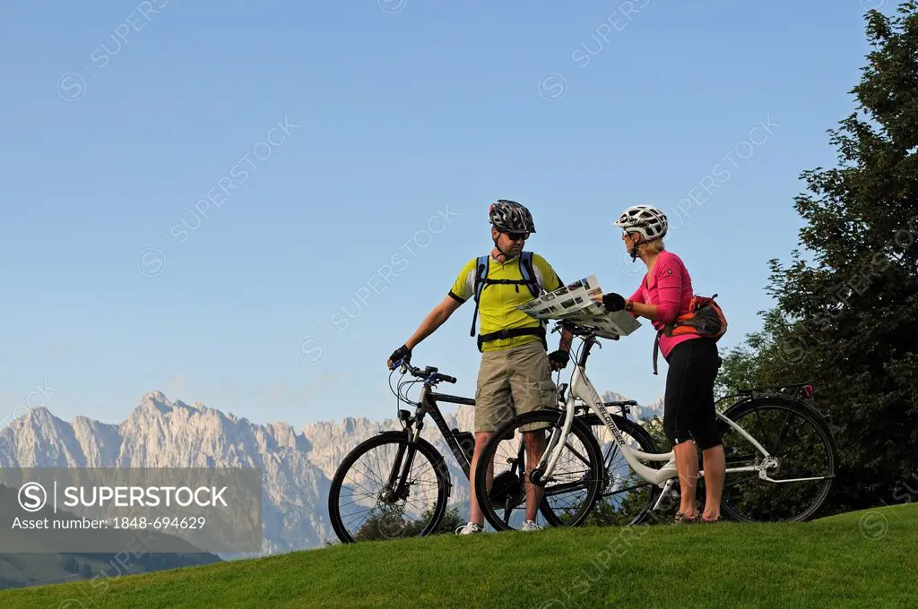 A couple riding electric bicycles, Wilder Kaiser mountain at the back, Reit im Winkl, Chiemgau, Upper Bavaria, Bavaria, Germany, Europe