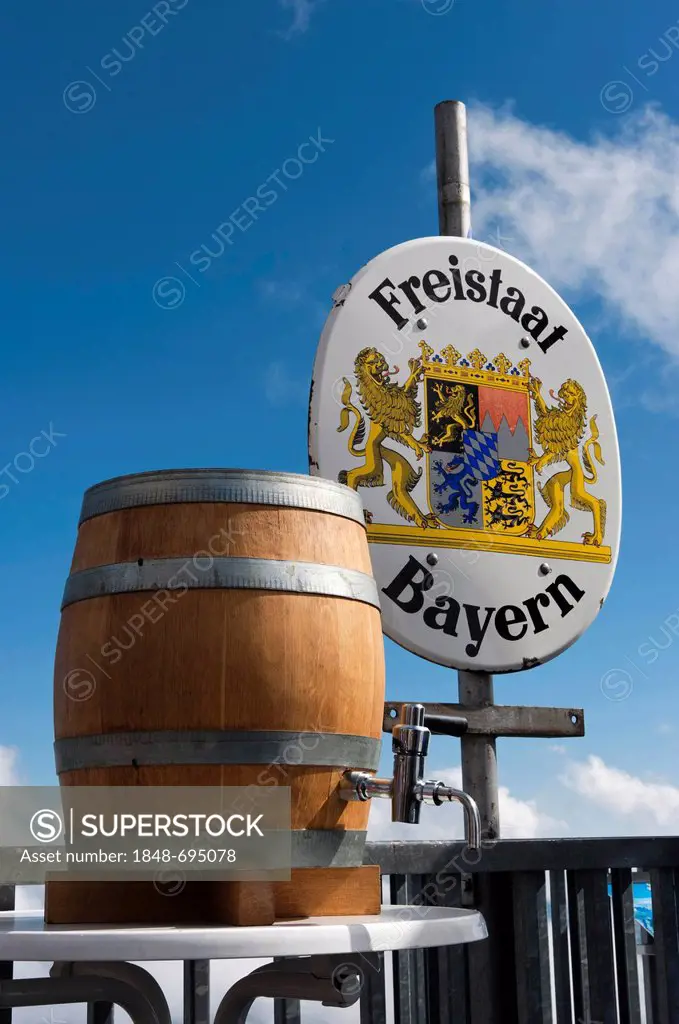 A barrel of beer standing in front of a border sign of the Freistaat Bayern or Free State of Bavaria, mountain station near the summit of Mt. Zugspitz...
