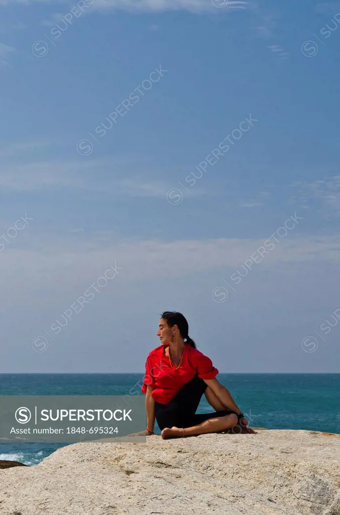 Woman in a yoga position, Ardha Matsyendrasana, by the sea in Kanyakumari, Tamil Nadu, India, Asia