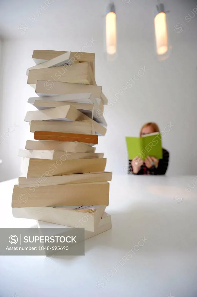 Stack of books in front of a reading woman