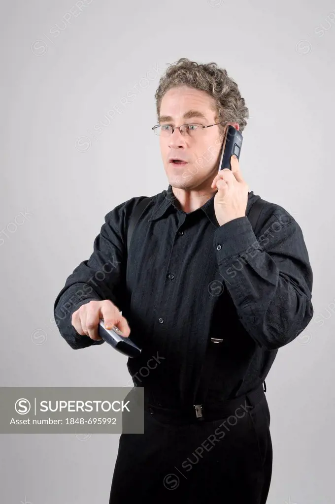 Businessman wearing a black suit using two mobile phones at the same time