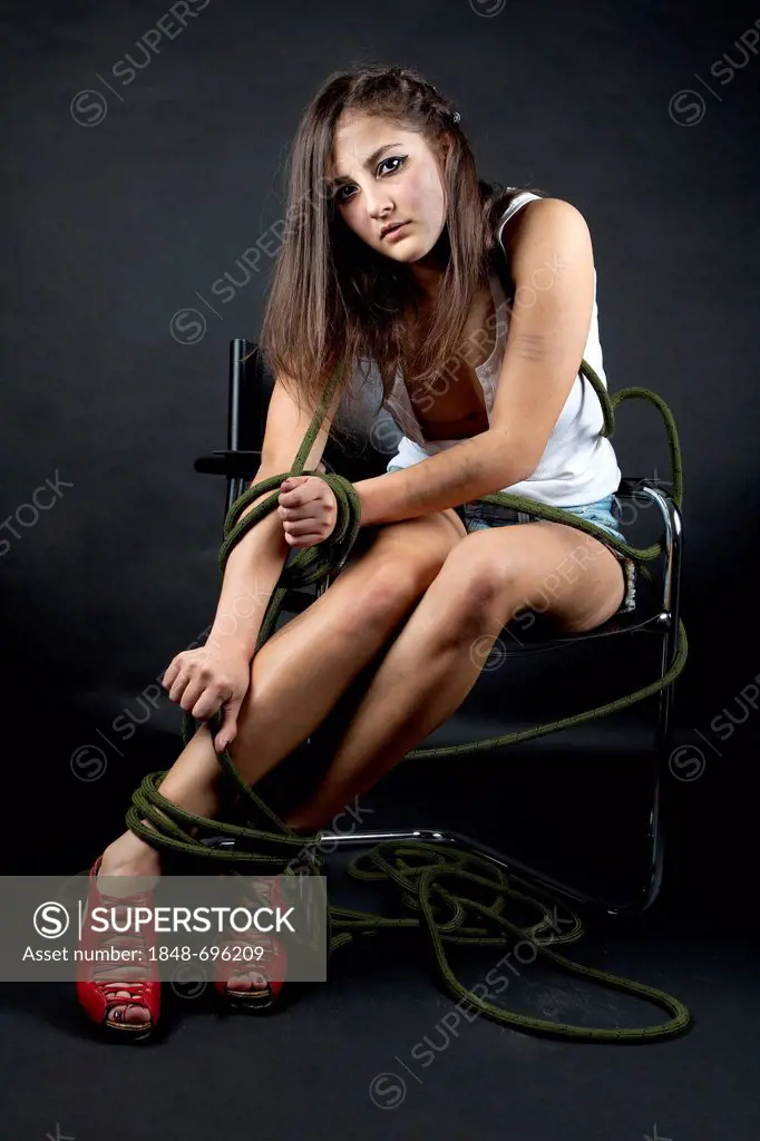 Young woman looking sad and dirty, tied to a chair