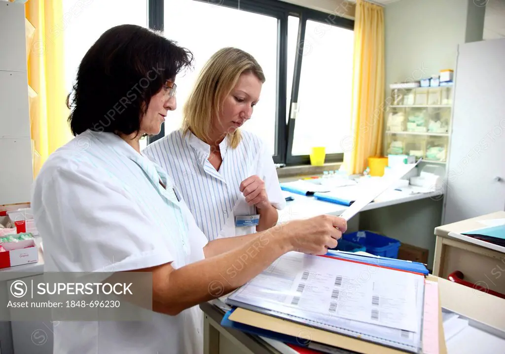 Nurses discussing the documents of patients in the nurse's station of a hospital