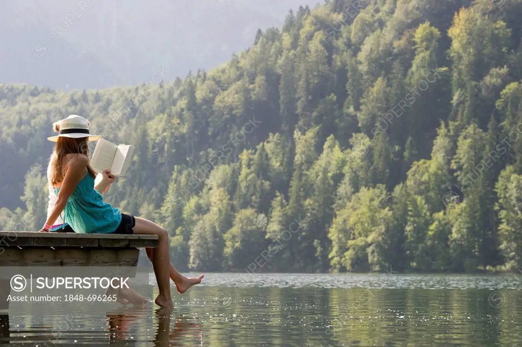 Young women sitting on a landing stage on Lake Schwansee near Fuessen, Allgaeu region, Bavaria, Germany, Europe