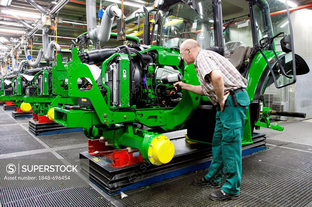Final inspection, man searching for a leak with a UV lamp in the tractor production section at the European headquarters of the American agricultural ...