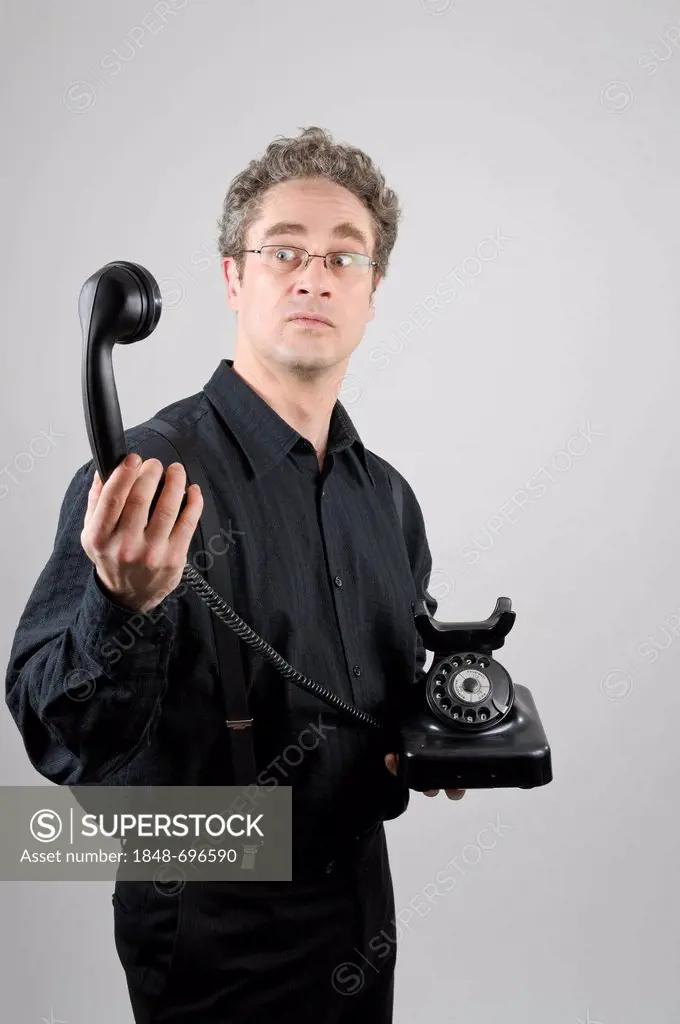 Businessman wearing a black suit holding a historical W 38 phone