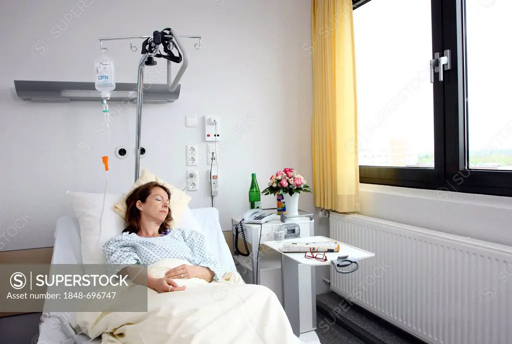 Patient lying in a hospital bed attached to a drip infusion, hospital