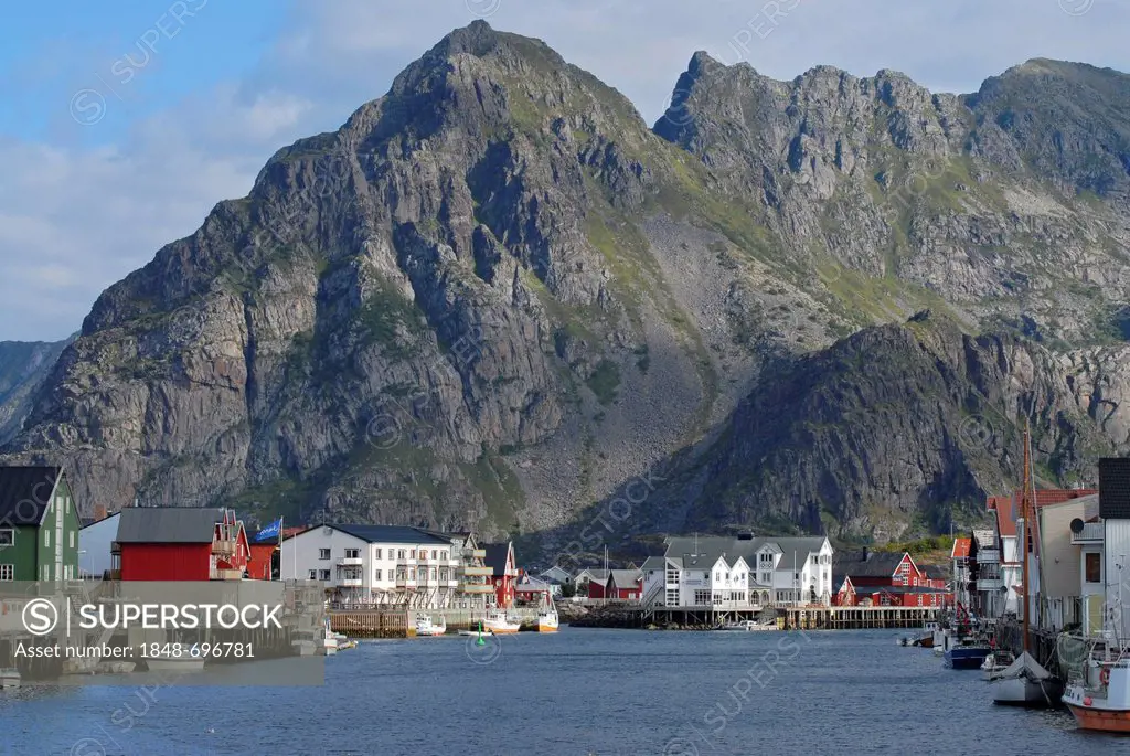 The steep rocks of the Lofoten archipelago behind the fishing boats and typical red and white houses in Henningsvær, Nordland, Norway, Europe