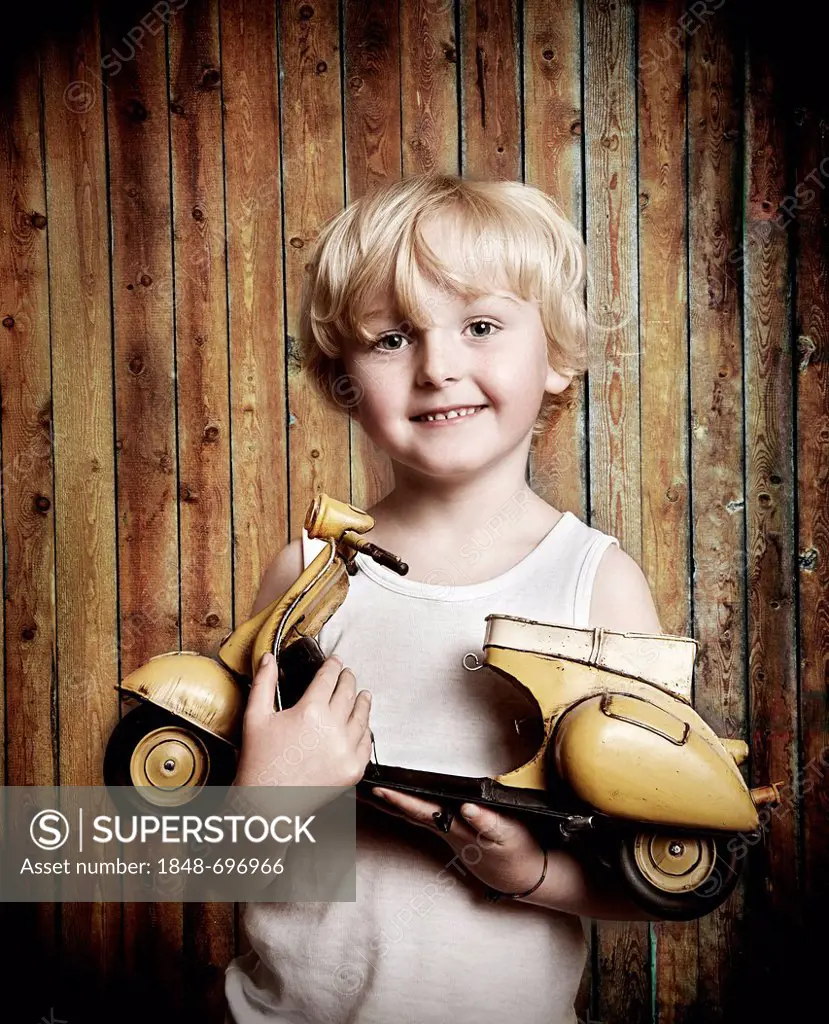 Five-year-old boy holding a toy Vespa scooter, gift, happy face