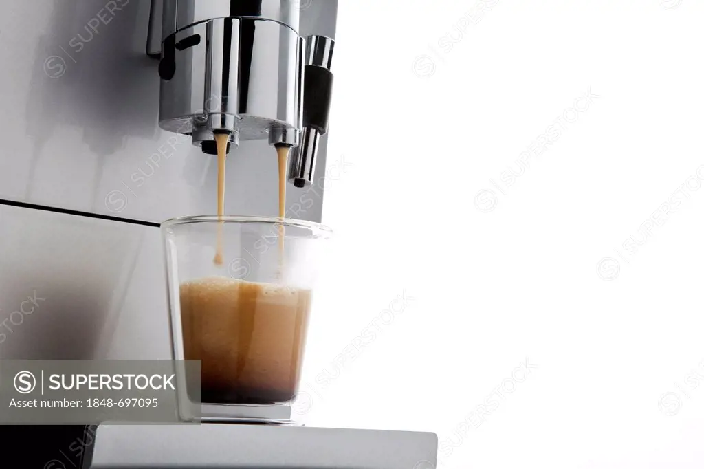 Coffee flowing from espresso machine into glass cup