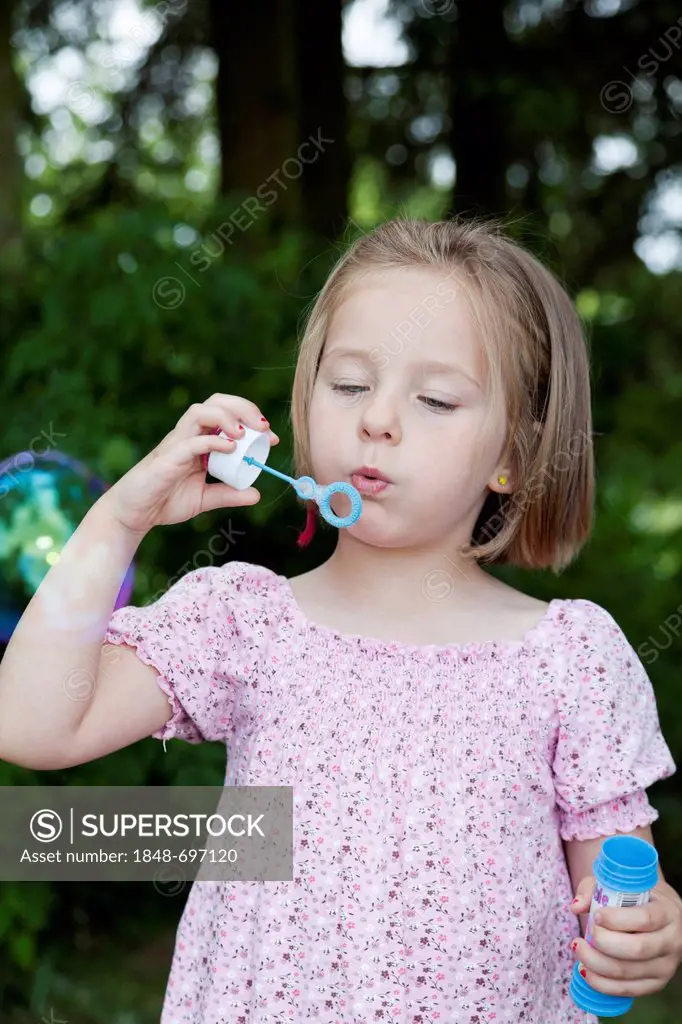 Girl, 4, blowing soap bubbles